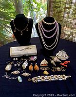 Overview of 20 pieces of vintage jewelry including necklaces, earrings, pins, brooches, and a mermaid trinket box on display.