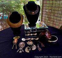Overview of all 12 pieces including two necklaces on busts, several pairs of earrings, bracelets, a mirrored jewelry box, and small vintage jewelry components.