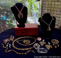 Full overview of the necklace, earrings, rings, brooches laid out on black cloth with cedar trinket box in background