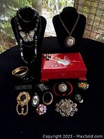 Full lot showing all jewelry pieces arranged around the red lacquer trinket box on black background.
