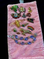 All vintage pins, brooches and bracelet laid out on pink velvet pouch, showing variety and condition.