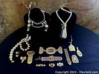 Full lot display of vintage jewelry pieces on black velvet stands and table. Includes beaded tassel necklace, pearl necklace, bracelets, pins, and pendants.
