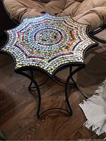 Full view of artistically designed mosaic glass table top with multi-point star edges and colorful circular mosaic pattern.