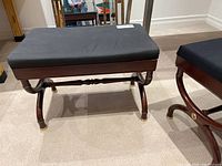 Wood bench with black cushioned top showing front and side views with curved wooden legs and brass accents.