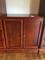 Front view of the wooden cabinet showing two paneled doors with round metal knobs.