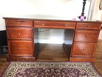 Front view of the wooden desk with five drawers and brass knobs.