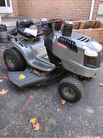 Front three-quarter view of silver lawn tractor with spare battery on hood