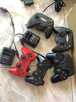 Photo showing five controllers and two Joytech chargers laid out on a tiled floor.