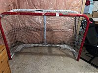 Front view of red steel hockey net with attached white netting showing scratches on frame.