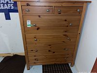 Front view of the dresser showing all 6 drawers with metal knobs and visible wood grain with knots.