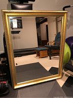 Front view of the entire framed mirror showing rectangular shape and gold ornate frame.