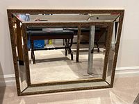 Front view of the ornate framed beveled mirror showing reflective surface and detailed border.