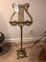 Full view of metal music stand showing lyre-shaped top and sturdy base on carpet.