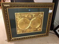 Framed vintage style world atlas print with sepia dual hemisphere map and decorative inset maps, ornate gilded frame with black accents.