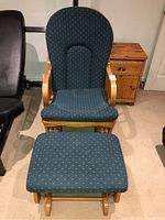 Front view of wooden rocker chair with blue fabric cushions and matching footstool on carpeted floor, showing condition and fabric pattern.