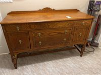 Full front view of the oak sideboard showing cabinetry, drawers, and brass handles.