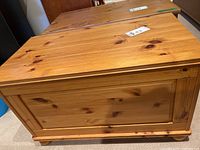 Wooden toy box closed showing natural wood finish and minor scratches.