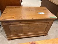 Closed wooden toy box showing natural wood grain, scratches visible on surface