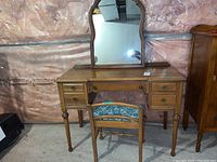 Front view of vintage wood vanity dresser with chair in front