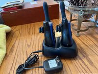 Two Motorola Talkabout T5500 walkie talkies standing in black charging dock with attached power adapter on tabletop.