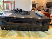 Front view of Yamaha RX-V595 AV receiver showing controls, volume knobs, input select buttons, and headphone jack.