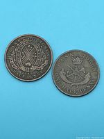 Two copper half penny tokens on blue background showing the obverse sides with emblems and inscriptions.