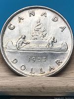 Reverse side of the 1953 Canadian silver dollar coin displaying the iconic canoe scene with two men paddling, the word CANADA above and the year 1953 below.