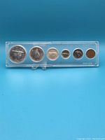 Full view of set of six Canadian Centennial coins in plastic holder on blue background.
