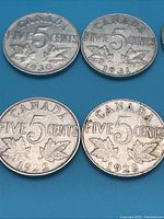 Close up of four Canadian 5 cent nickels dated 1930, 1931, 1922, and 1928 with maple leaf design on reverse and 'Canada Five Cents' text.