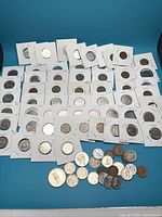 Photo showing a wide variety of Canadian coins mostly in 2x2 holders along with loose coins laid out on a blue surface.