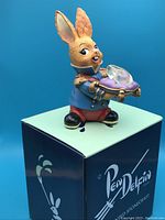 Front view of the Pendelfin Charming rabbit figurine on the branded teal box showing the facial features, clothing, and crystal slipper.