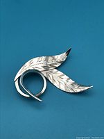 Front view of sterling silver leaf brooch showing two etched leaves and curled stem