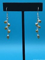 Front view of one sterling silver earring showing multiple small round yellow stones in a vine shape hanging from a hook.