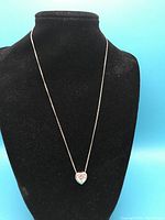 Chain and heart pendant displayed on black velvet necklace stand against blue background to show overall appearance and length.