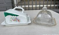 Full view of porcelain covered cheese dish and pressed glass covered plate side by side.
