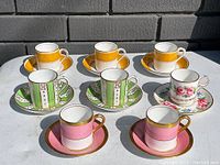 Eight demitasse cups and their matching saucers, arranged in four distinct pairs by design against a neutral background.