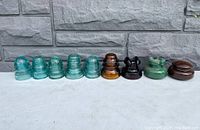 Nine insulators lined up against grey stone background
