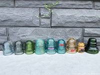 All nine insulators arranged in a row against a stone wall background
