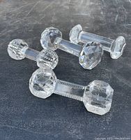 Four antique cut crystal faceted knife rests arranged on dark surface, showing varied faceted and etched end patterns