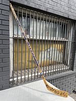 Full-length view of the wooden hockey stick with 'WINNIE' and 'PRO STOCK' markings, positioned vertically showing the entire stick.