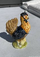 Side view of Beswick Beatrix Potter Henny Penny figurine showing hen with bonnet and chicks on grassy base