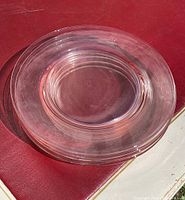 Close side view of pink Depression glass plates stacked to show thickness and smooth rounded edges.