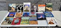 Photo of 16 vintage coffee table books laid out on the floor with titles and covers visible, showcasing a variety of subjects such as architecture, historical buildings, travel and fiction.