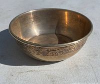 Angled view of round sterling silver bowl with floral engraved band under rim, showing interior and side.