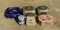 Top view of six vintage trinket boxes showing various materials and painted designs.