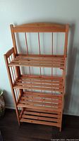 Front view of assembled 4 tier wooden folding shelf with slatted shelves and natural wood finish.