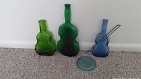 Three antique violin-shaped glass bottles on carpet with vintage lid and metal wire