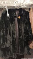 Front view of dark green shared beaver fur coat showing the button closure and texture.