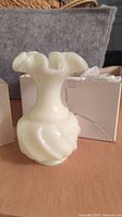 White handmade ruffled top vase with twisted bubble body design and glossy finish, placed on wooden surface with white boxes in the background.