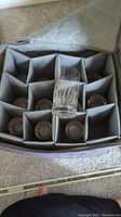 12 crystal water glasses stored upright in a gray padded carrying case with individual compartments.